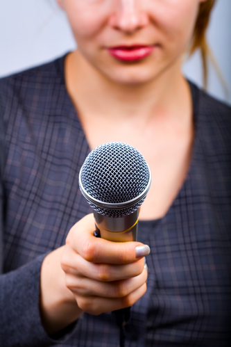 Kvindelig interviewer står med mikrofon.