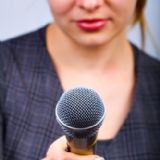Kvindelig interviewer står med mikrofon.