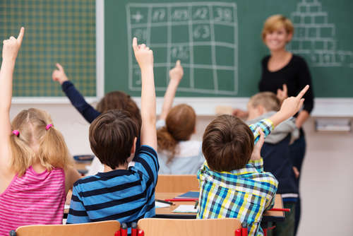 Skoleelever rækker alle hånden op i klassen