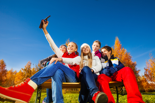 Teenagere sidder på en bænk og er ved at tage en selfie