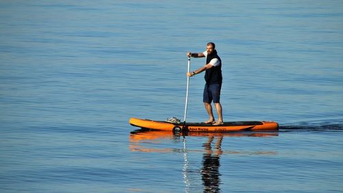 Mand på orange SUP board på vandet