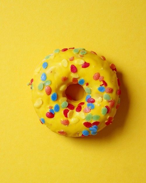 Gul donut med mulitfarvede krymmel på gul baggrund