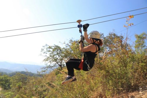 Smilende kvinde i zipline en solskinsdag