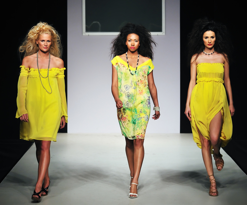 3 unge modeller går modeshow / catwalk klædt i gule designerkjoler