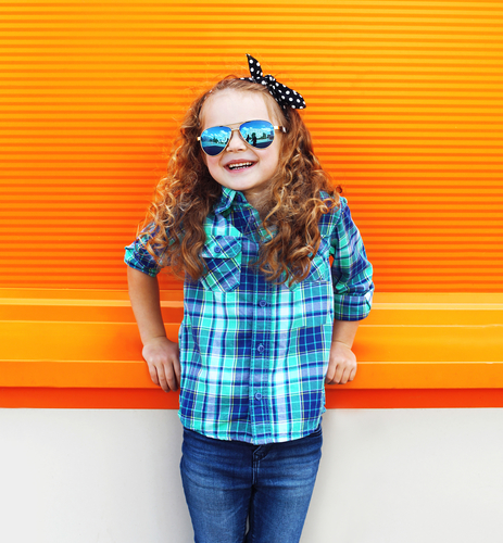 Smilende pige med solbriller står op af orange baggrund