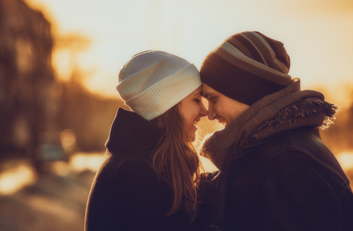 Smilende par står i vinterkulden med panderne mod hinanden