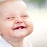 Storsmilende baby med en tand i munden
