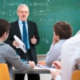Foto af mandlig lærer, der står oppe ved tavlen med matematiske formler bag sig.