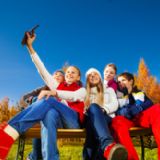 Teenagere sidder på en bænk og er ved at tage en selfie