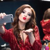 Kvinde i rød palietkjole tager selfie foran et spejl