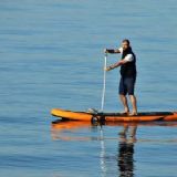 Mand på orange SUP board på vandet