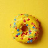 Gul donut med mulitfarvede krymmel på gul baggrund